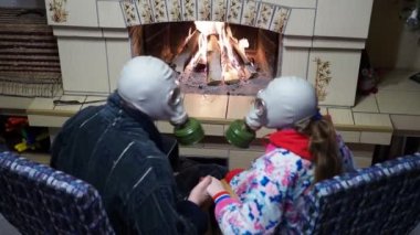 Salgın, Covid-19. Bir erkek ve bir kadın, şöminenin yanında koruyucu gaz maskeleriyle oturmuş birbirlerinin ellerini tutuyor ve birbirlerine yaslanıyorlardı..