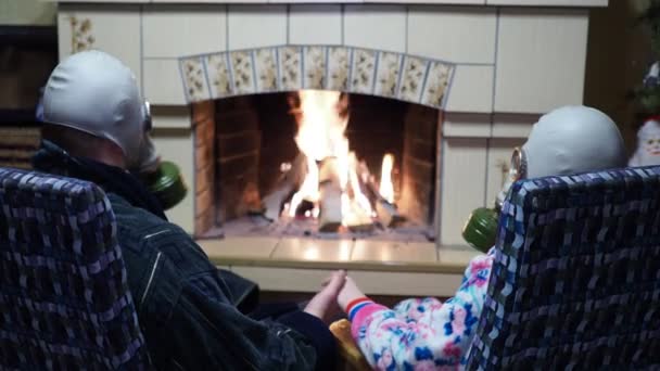 感染症 コヴィト 男と女が暖炉の近くの防護ガスマスクに座って手を取り合って寄り添っている — ストック動画