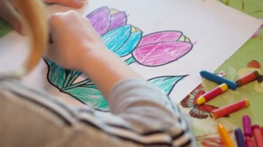 Çocuklar işte. Çizimi renkli kalemlerle dikkatlice çizen küçük bir kızın elleri. Yakın çekim..