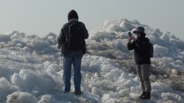 Küçük bir buzdağının üzerinde dikilirken telefonuyla fotoğraf çeken genç bir kadın Ob Nehri 'ne (Sibirya) vurmuş.).