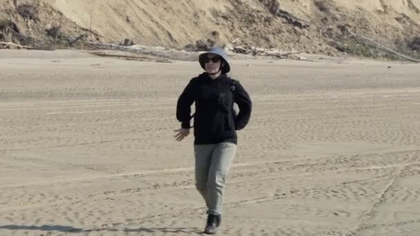帽子を被った笑顔の幸せな女性がオブ川 シベリア の砂州沿いを歩いている — ストック動画
