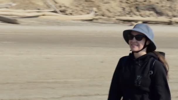 一个戴着帽子的笑容满面的快乐女人沿着奥布河 西伯利亚 的沙滩边走着 后续行动 — 图库视频影像