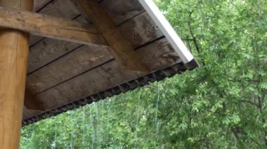 Soyutlama. Çatıdan düşen su damlaları yeşil yaprakların arka planına çarpıyor.