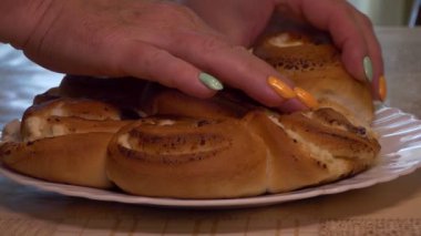 Yiyecek, un ürünleri. Kadınların elleri taze pişmiş çörekleri süzme peynirle kırar. Yakın plan..