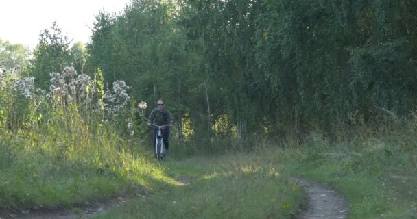 骑自行车 一个年轻的女人骑自行车在泥泞的山林路上 西伯利亚 — 图库视频影像