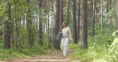 Yolculuk. Beyaz elbiseli güzel bir kadın çam ormanında bir patika boyunca yürüyor. Sibirya.