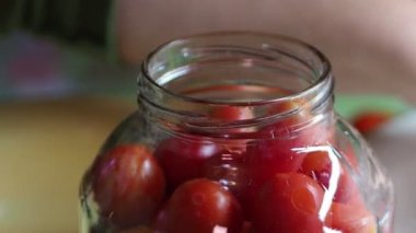 Ev konservesi. Bir kadın muhafaza etmek için domatesleri cam kavanoza koyar. Yakın plan. Elle çekim (el kamerasıyla çekim)).
