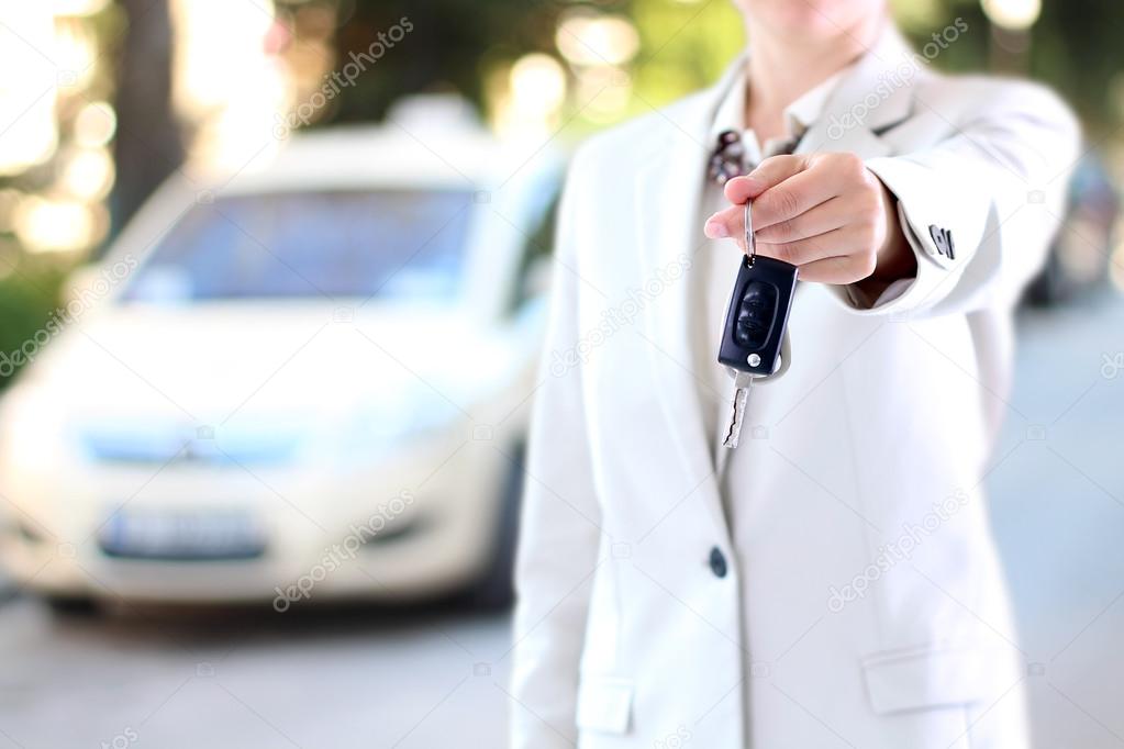 Young successful businesswoman offering a car key.