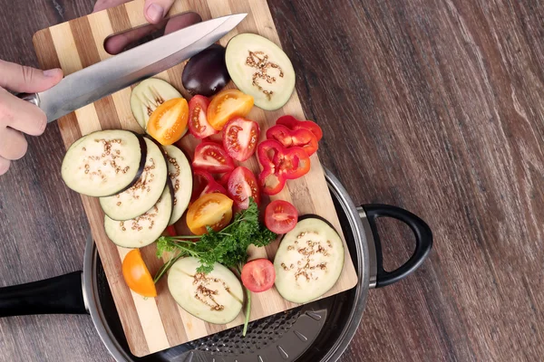 Färska grönsaker på skärbräda faller i pannan. Begreppet matlagning. — Stockfoto