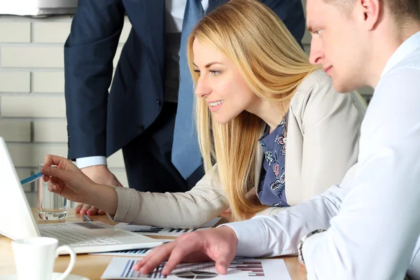 Collega's samenwerken en analyseren van financiële cijfers op een laptop — Stockfoto