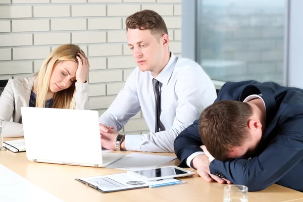 Un travail ennuyeux. Les jeunes gens d'affaires qui ont l'air ennuyés assis ensemble à la table et regardant ailleurs — Photo