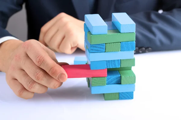 Planning, risk and strategy in business, businessman getting out a wooden block from a tower — Stock Photo, Image