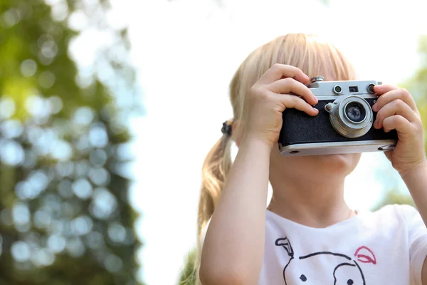 Little girl taking picture using vintage film camera