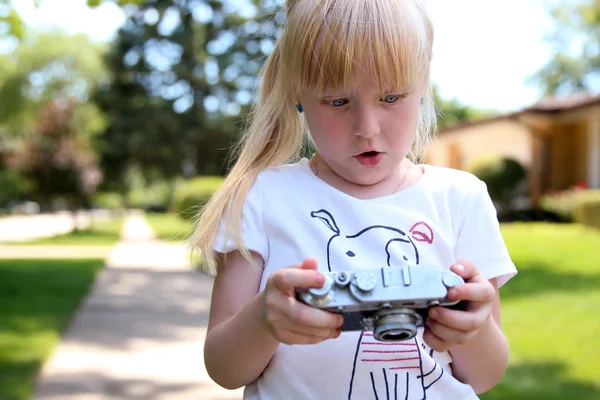 Little girl looking  with a big suprise to a vintage film camera — Stock Photo, Image