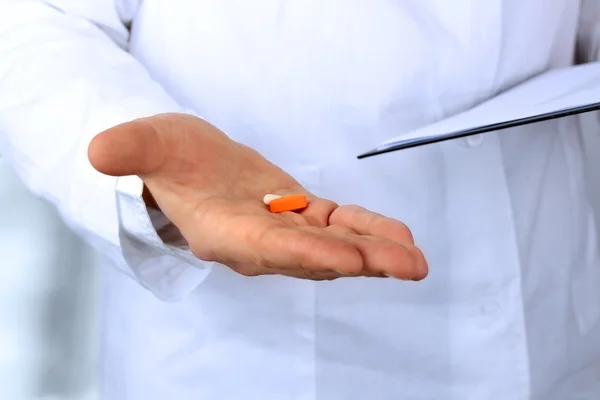 Médico en un labcoat blanco dando pastillas —  Fotos de Stock
