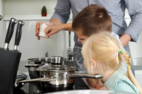 Small boy with girl l salting food with  father in the kitchen — Stock Photo, Image