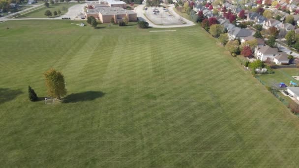 ゆっくりと芝生の草刈りプロセスで様々な学校や地域のフィールドの上を飛んでいます アメリカ郊外 — ストック動画