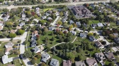 Chicago 'nun banliyö caddesi boyunca uzanan drenaj gölü olan renkli sonbahar ağaçlarının, konutların ve bahçelerin yukarıdan görünüşü. Amerika 'nın orta batısında. 4K
