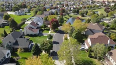Chicago 'nun banliyö caddesi boyunca uzanan drenaj gölü olan renkli sonbahar ağaçlarının, konutların ve bahçelerin yukarıdan görünüşü. Amerika 'nın orta batısında. 4K