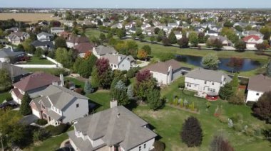 Chicago 'nun banliyö caddesi boyunca uzanan drenaj gölü olan renkli sonbahar ağaçlarının, konutların ve bahçelerin yukarıdan görünüşü. Amerika 'nın orta batısında. 4K