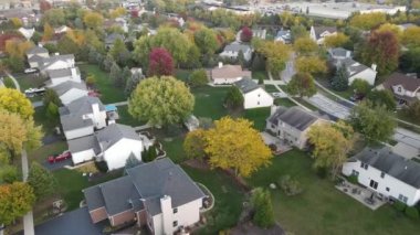 Chicago 'nun banliyö caddesi boyunca uzanan drenaj gölü olan renkli sonbahar ağaçlarının, konutların ve bahçelerin yukarıdan görünüşü. Amerika 'nın orta batısında. 4K