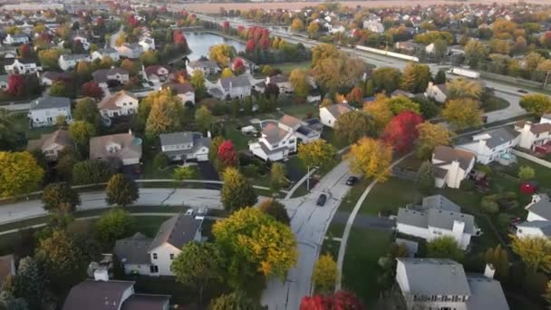 Overhead aerial view of colorful autumn trees, residential houses and yards with drainage pond along suburban street in Chicago area. Midwest USA. 4K — Stock Footage Overhead Aerial View Colorful Autumn Trees Residential Houses Yards Drainage Royalty Free Stock Footage