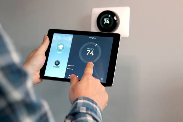 Mann Stellt Temperatur Mit Tablet Mit Smart Home App Modernen lizenzfreie Stockbilder