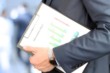 İşadamı ayakta ve elinde grafik tutarak .