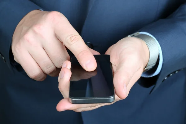 Empresario sosteniendo y utilizando el teléfono inteligente móvil — Foto de Stock