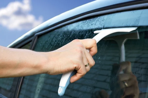 Trabajador lavando la ventana del coche con un rascador —  Fotos de Stock