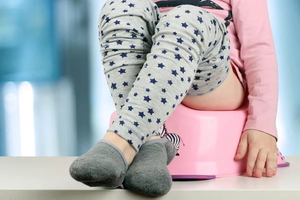 Children's benen opknoping neer uit een kamer-pot op een blauwe terug — Stockfoto