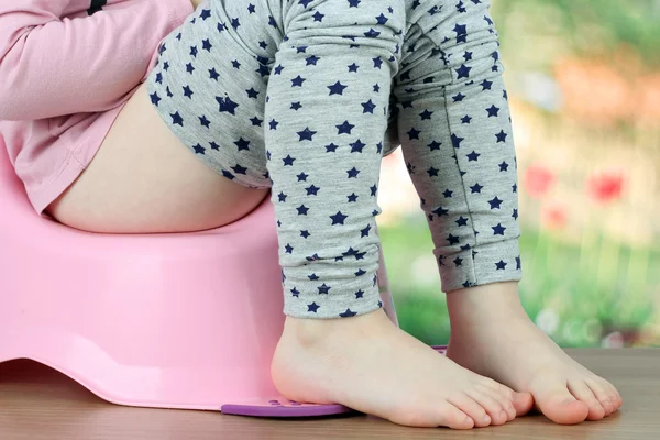 Children's legs hanging down from a chamber-pot on a green backg — Stock Photo, Image