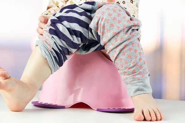 Kinderbeine hängen von einem Kammertopf herunter — Stockfoto