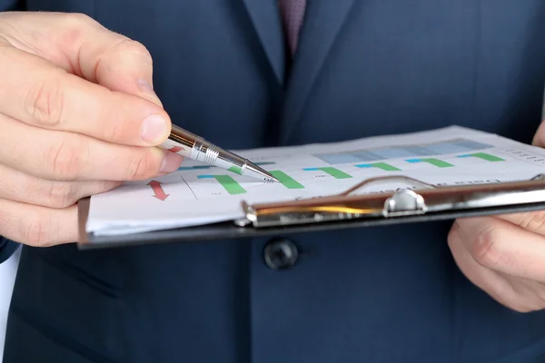 Young businessman showing graphs by pen — Stock Photo, Image