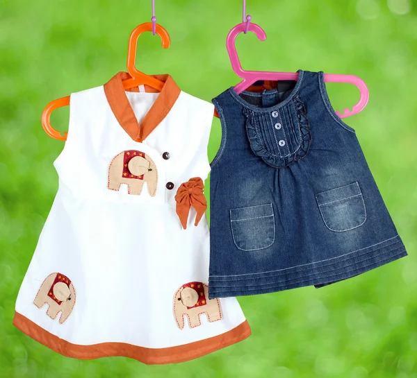 Fashion baby dresses hanging on a hanger on a  green background — Stock Photo, Image