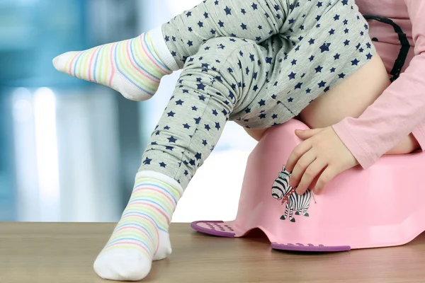 Niño sentado en un orinal sobre un fondo azul —  Fotos de Stock