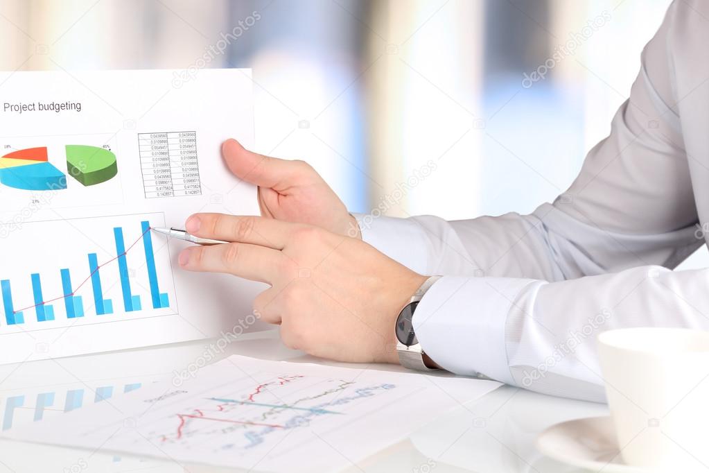 Businessman sitting and showing something on a  graphic by pen .