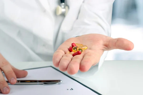 Médico en un labcoat blanco dando pastillas —  Fotos de Stock