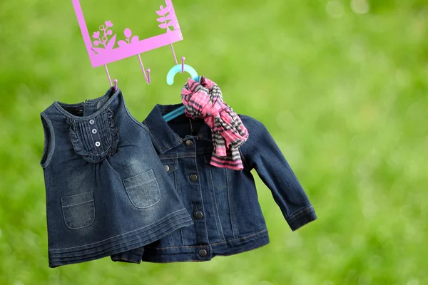 Fashion baby dresses hanging on a hanger on a green  background — Stock Photo, Image