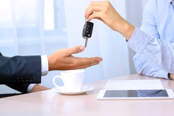 Vendedor de carros entregando as chaves para um carro novo para um jovem busi — Fotografia de Stock