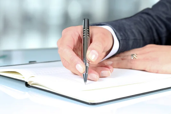 Vrouw hand met behulp van een pen vaststellend op Kladblok — Stockfoto