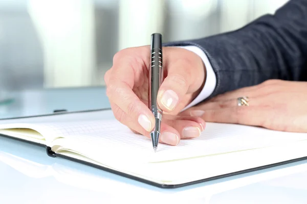 Woman's hand using a pen noting on notepad Royalty Free Stock Photos