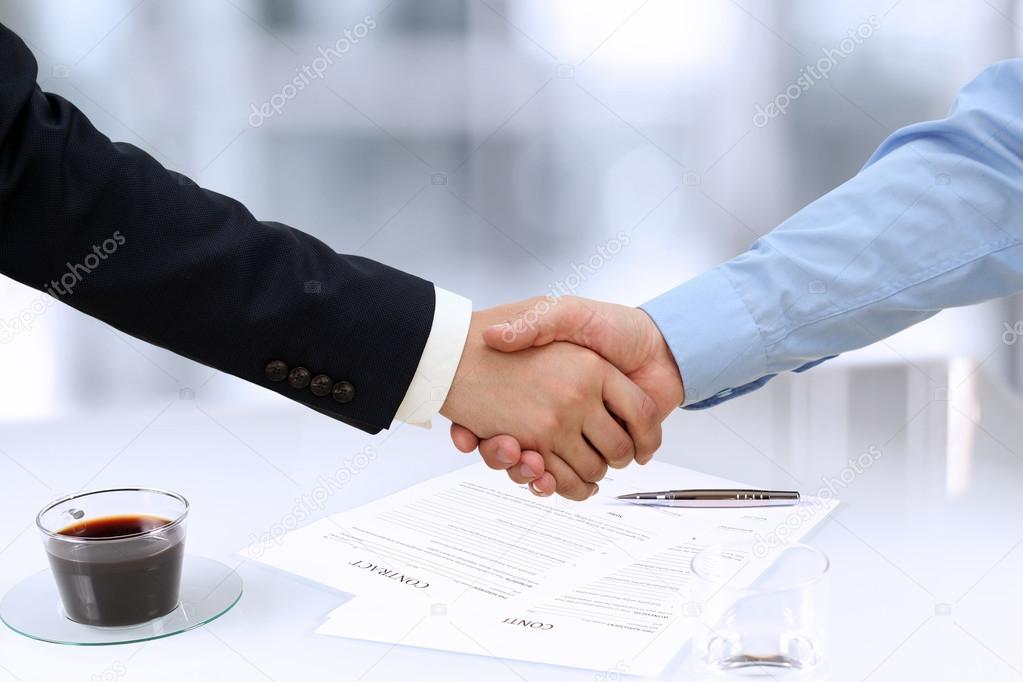 Close-up image of a firm handshake  between two colleagues in office.