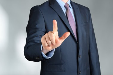 Bisinessman s bir şey el ile dokunmak modern takım elbiseli. yanında gri arka plan