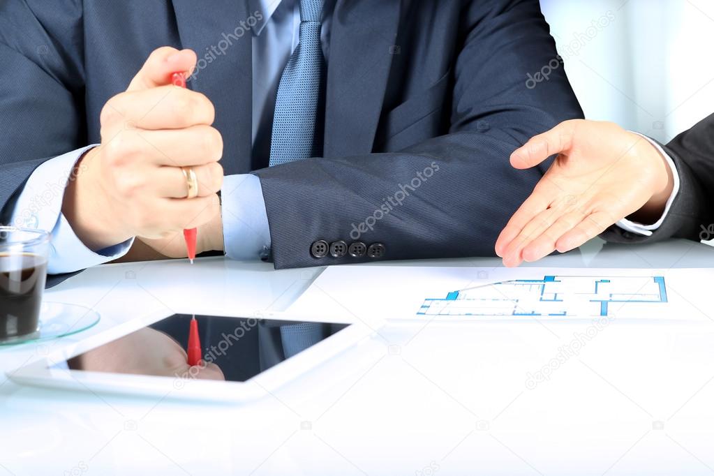 Real-estate agent showing house plans to a businesssman. Focus on a hand