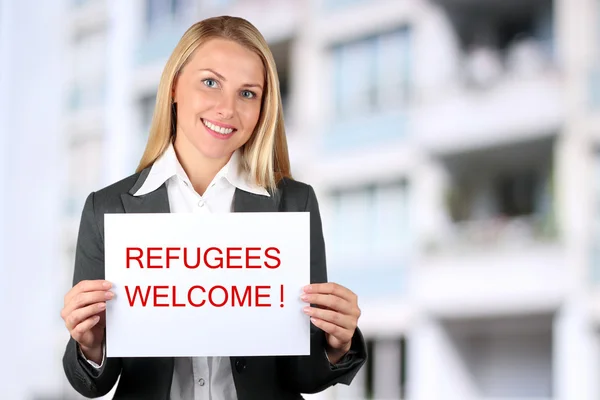 Lachende vrouw met een witte banner met de woorden "Welkom vluchtelingen" — Stockfoto