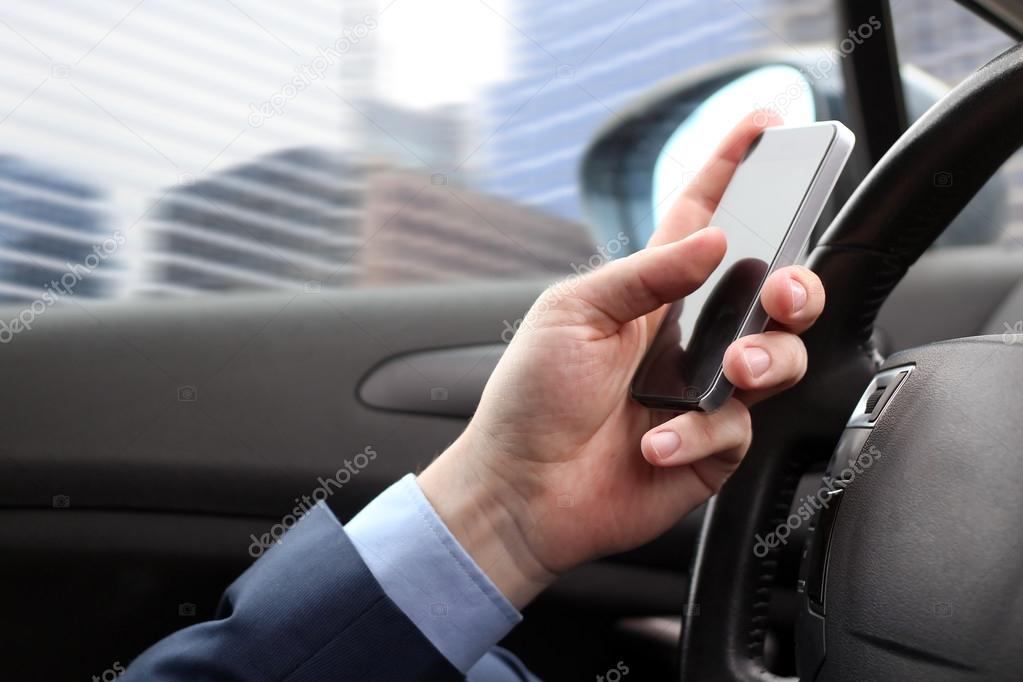The businessman using mobile smart phone while driving the car