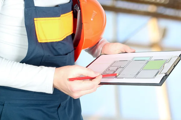 Trabajador en una obra de construcción tiene un proyecto de un piso — Foto de Stock