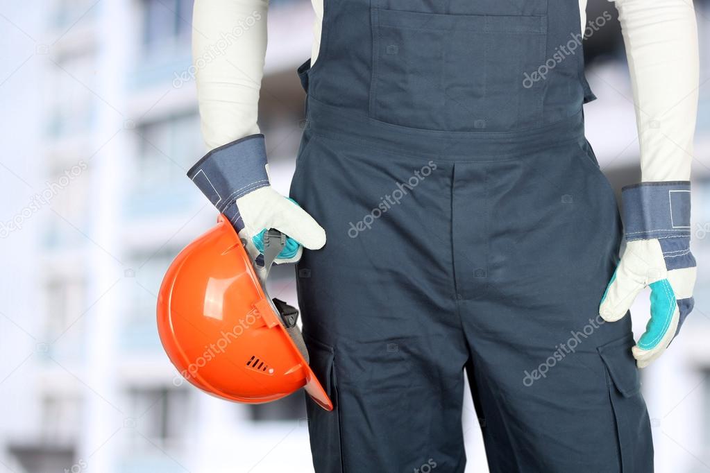 Worker in a construction site holds a helmet