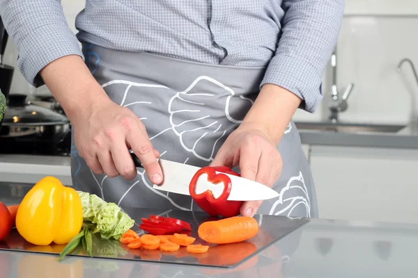 Essen, Familie, Kochen und Menschen-Konzept - Mann schneidet Paprika auf Schneidebrett mit Messer in Küche — Stockfoto